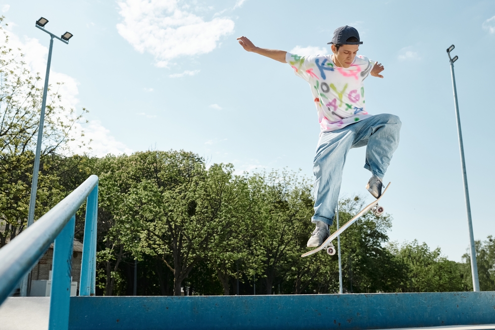 Skateboarder Jump Trick Over Rail Outdoors - Thomas Augusto Skateboarder performing a jump trick over a rail in an outdoor skatepark, emphasizing skill and athleticism. - Thomas Augusto